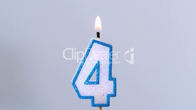 Four birthday candle flickering and extinguishing on blue background