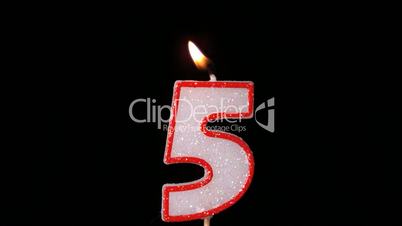 Five birthday candle flickering and extinguishing on black background