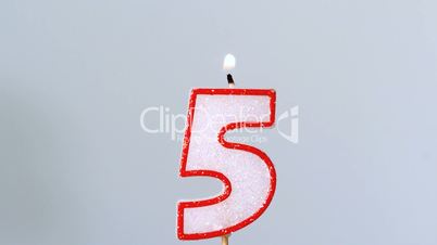 Five birthday candle flickering and extinguishing on blue background