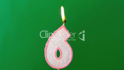 Six birthday candle flickering and extinguishing on green background