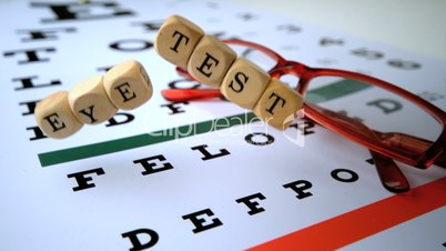 Eye test dice falling onto eye test with red reading glasses