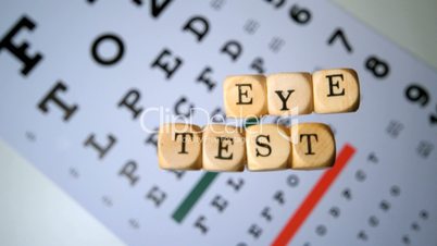 Dice spelling out eye test falling onto eye test beside glasses