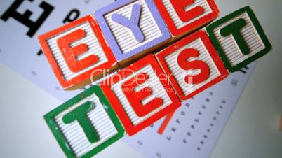 Blocks spelling out eye test falling onto eye test