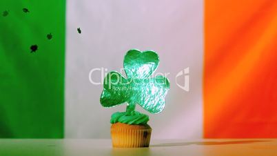 Shamrock confetti falling on st patricks day cupcake