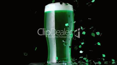 Shamrock confetti falling in front of pint of green beer