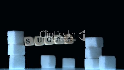 Dice spelling out sugar falling beside sugar cubes