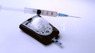 Syringe falling onto pile of sugar on blood glucose monitor