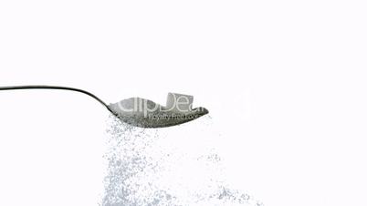 Sugar spilling off spoon with sugar and sugar cube