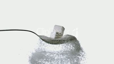 Sugar cubes falling onto spoon full of sugar