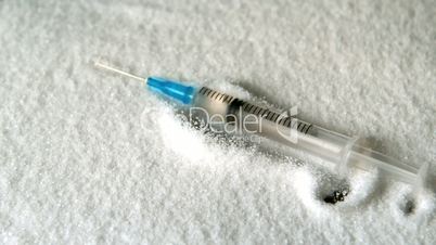 Syringe falling into pile of sugar