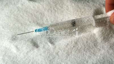 Hand taking syringe out of pile of sugar