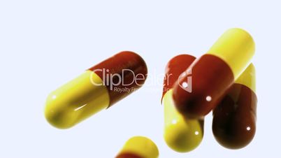 Red and yellow capsule tablets dropping and bouncing close up