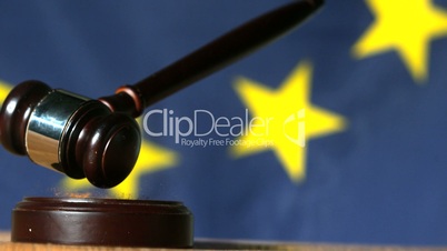 Gavel falling onto sounding block with european union flag in background