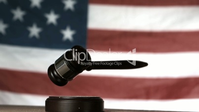 Gavel dropping onto sounding block with american flag in background