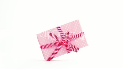 Pink gift wrapped present coming on screen and turning with copy space