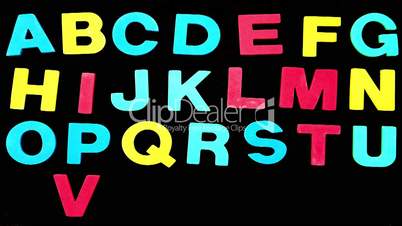 Colourful alphabet appearing on black background