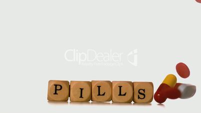 Many types of pills pouring over dice spelling pills