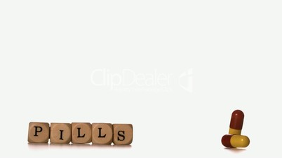 Two capsule tablets falling beside dice spelling pills