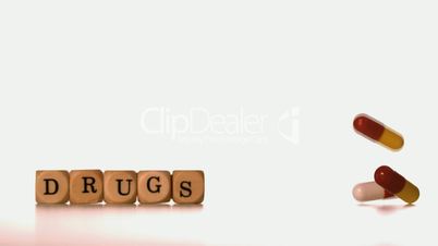 Different tablets falling beside dice spelling drugs