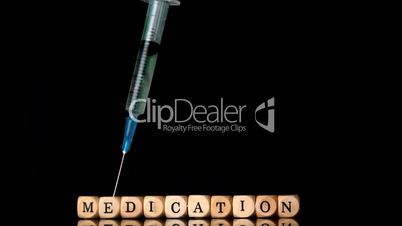 Syringe falling in front of dice spelling medication on black background