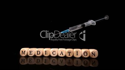 Syringe falling and rolling over dice spelling medication