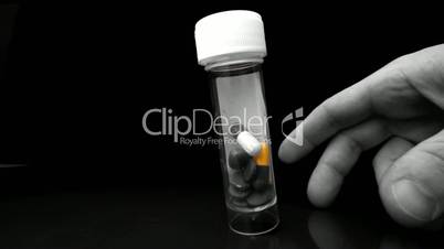 Hand shaking plastic jar of medicine in selective black and white