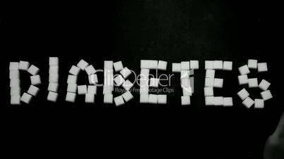 Hand pushing away diabetes spelled in sugar cubes