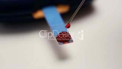 Needle placing drop of blood on test strip of glucose monitor