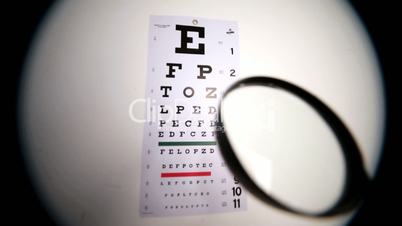 Someone holding magnifying glass up to eye test