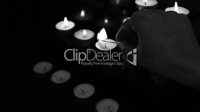Hand using match to light candles for worship