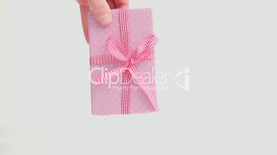 Hand putting down pink gift wrapped present and then taking it away