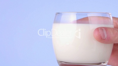Hand taking away glass of milk close up