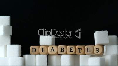 Sugar cubes and dice spelling diabetes falling down in black background over sugar cubes wall