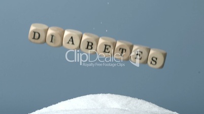 Dice spelling out diabetes falling over pile of sugar