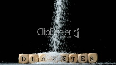 Sugar powder being poured over dice spelling out diabetes