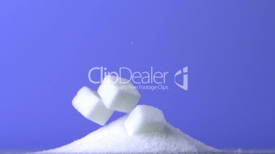 Sugar cubes falling down into pile of sugar on purple background