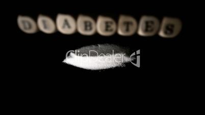 Dice spelling diabetes falling over a pile of sugar on black surface