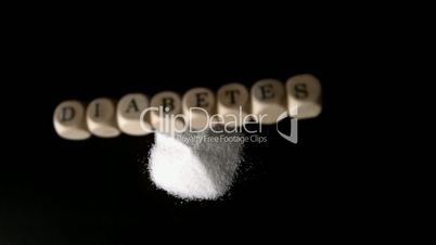 Dice spelling out diabetes falling over a pile of sugar