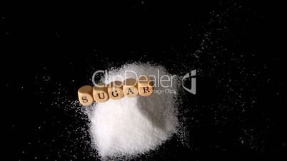 Dice spelling out sugar falling in a pile of sugar