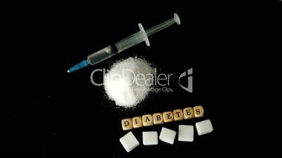 Syringe falling into pile of sugar besides dice spelling out diabetes and sugar cubes