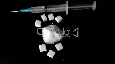 Syringe of insulin falling into pile of sugar next to sugar cubes