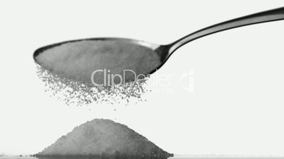 Spoon pouring sugar powder on pile of sugar