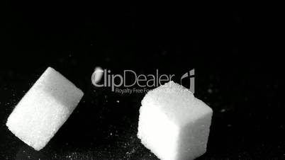 Sugar cubes falling on hard black surface