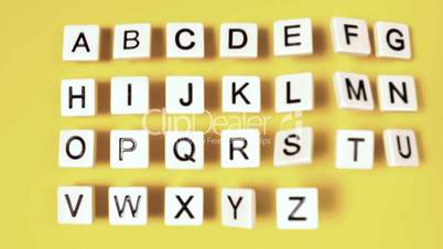Plastic letters bouncing and showing alphabet on yellow surface