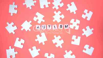 Plastic letters bouncing and spelling out autism next to jigsaw puzzle