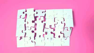 Jigsaw puzzle falling on pink surface