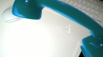 Blue receiver falling onto a white desk