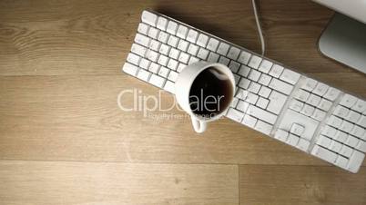 Cup of tea spilled out over a white keyboard