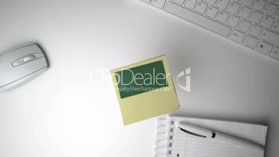 Yellow post it with green copy space falling on office desk