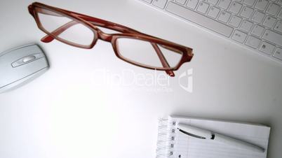 Red glasses falling onto an office desk